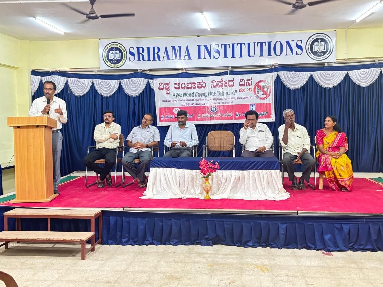 Staff and invited guests seated on stage beneath a Srirama Institutions banner during the World No Tobacco Day programme