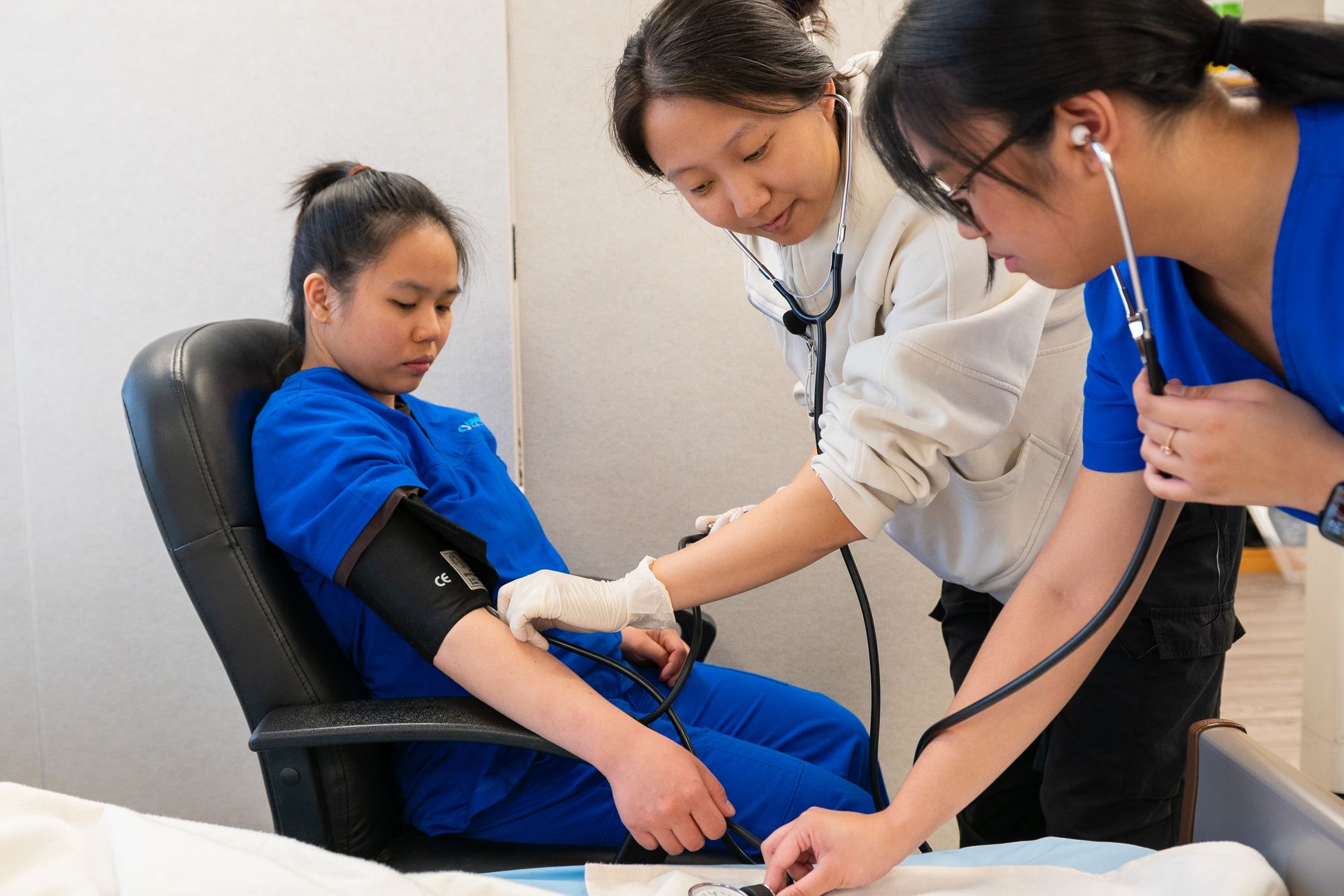 Two trainees taking a seated person’s blood pressure under supervision