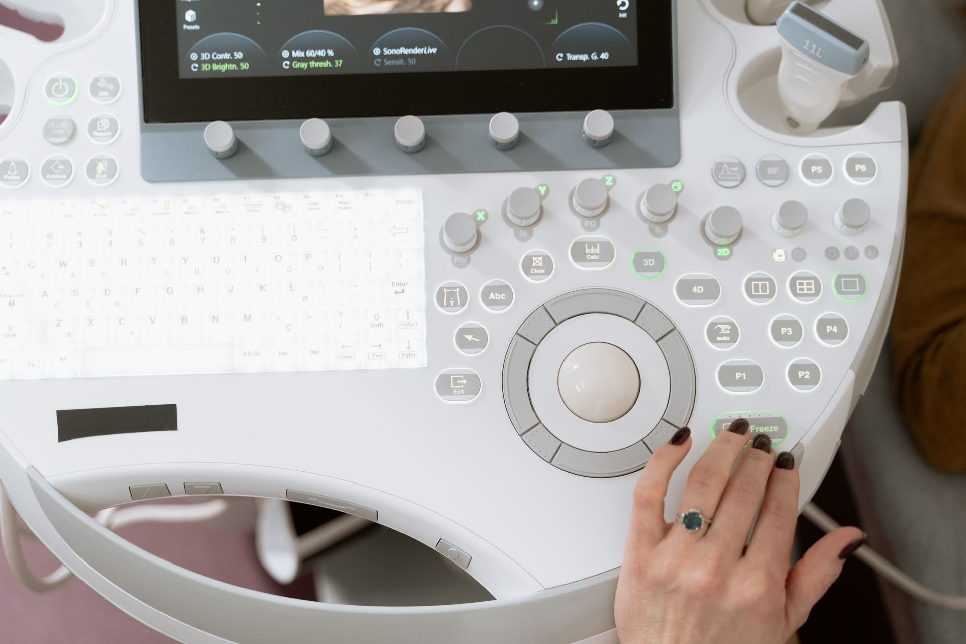 A hand operating the control panel of an ultrasound scanner