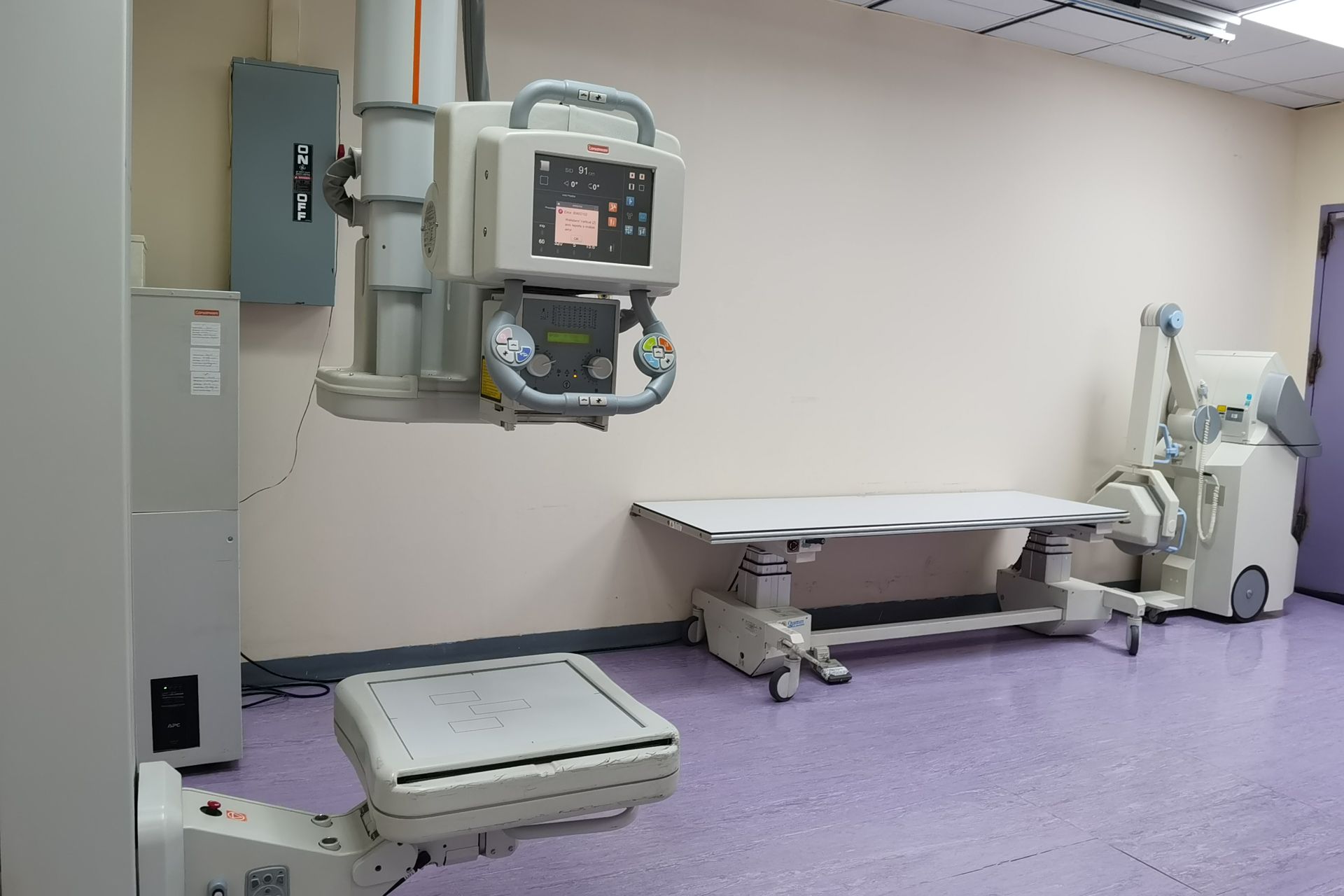 A radiography room with an X-ray tube mounted above an examination table