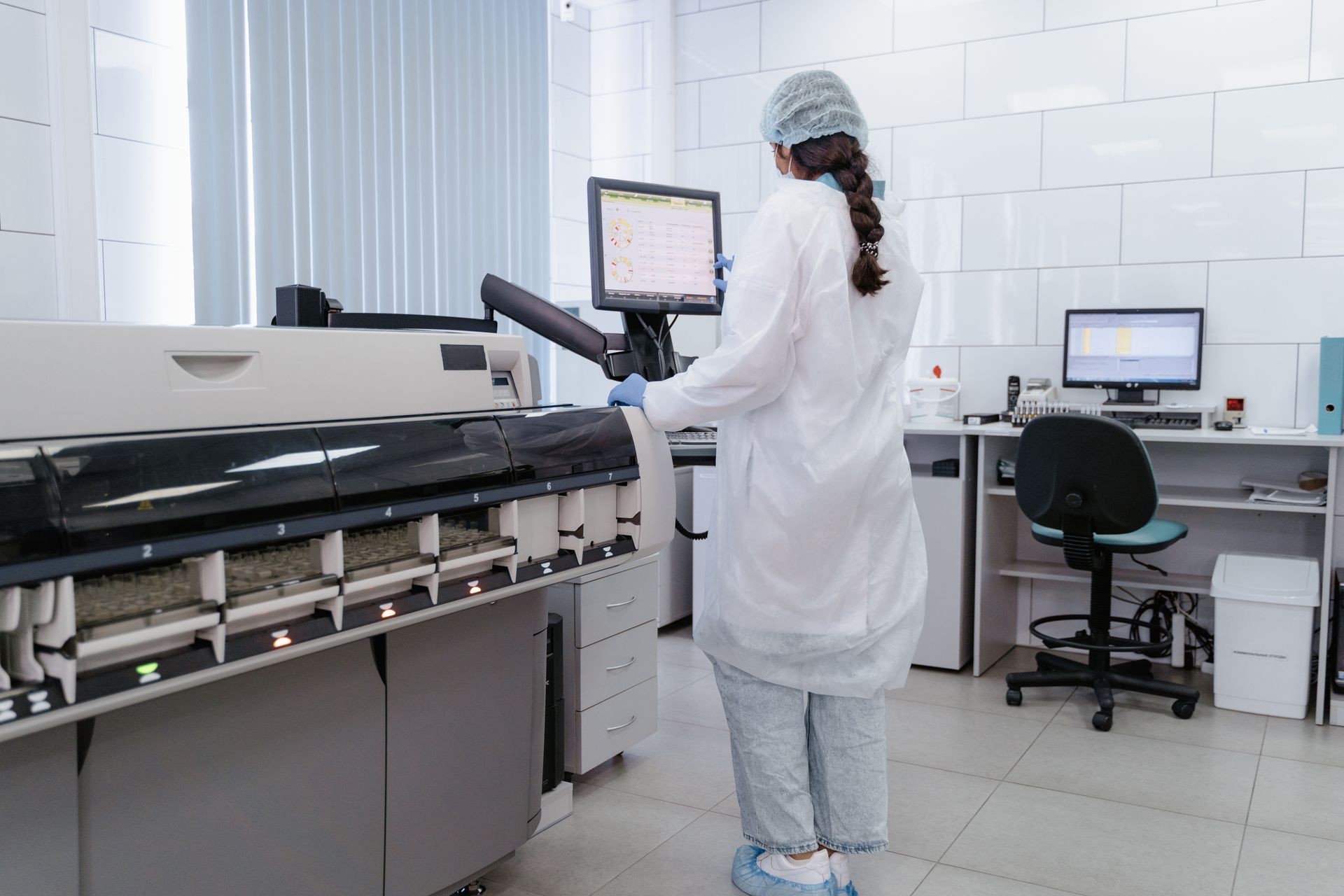 A technician operating an automated analyser in a diagnostic laboratory
