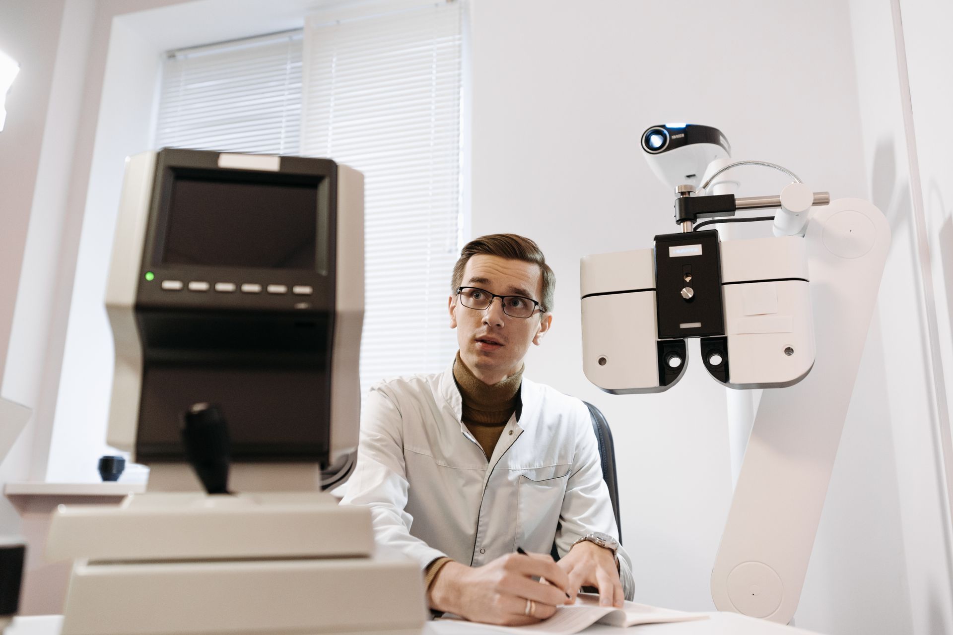 An optometrist at a vision-testing instrument in a consulting room